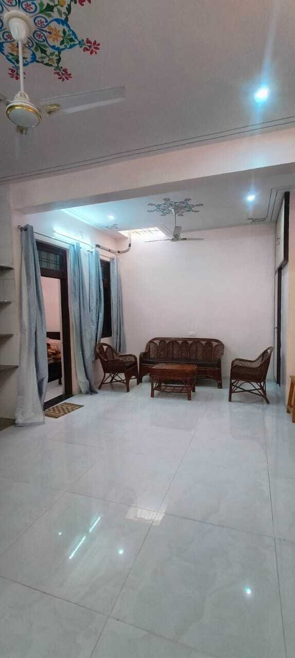 Bright living room with cane sofa set, glossy tiled flooring, curtains, modern lighting, and decorative ceiling fan