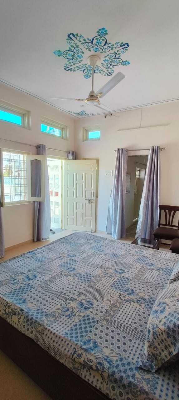 Minimalist bedroom with wooden double bed, side tables, patterned bedding, and decorative ceiling fan design