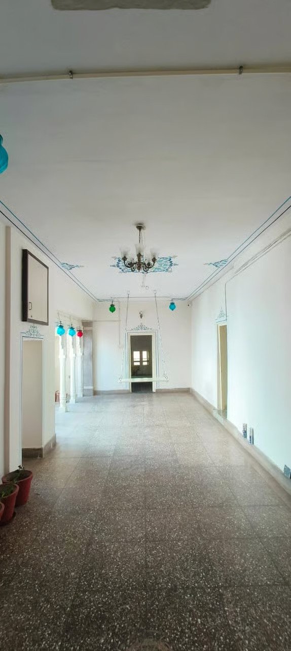 Spacious home corridor with terrazzo flooring, white walls, decorative ceiling lights, and natural daylight